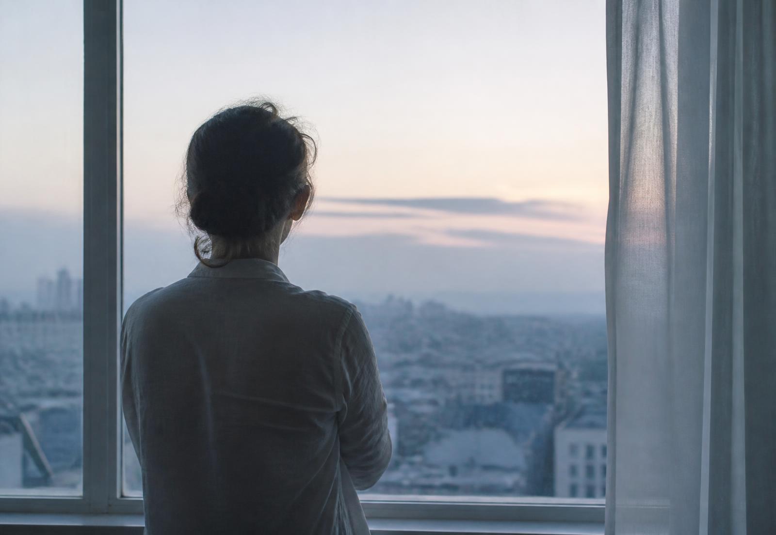 Person at a window at dawn in quiet contemplation